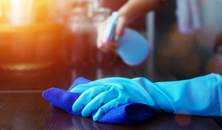 戴着蓝色手套，用布喷洒清洗液